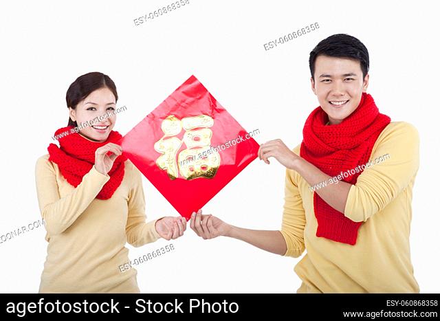 Portrait of young couple holding a Chinese Good Luck Fu, paying New Year call