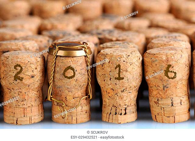 Closeup of a large group of Champagne corks, that fill the frame with the date 2016. Selective focus on the front row. One cork has the metal cage
