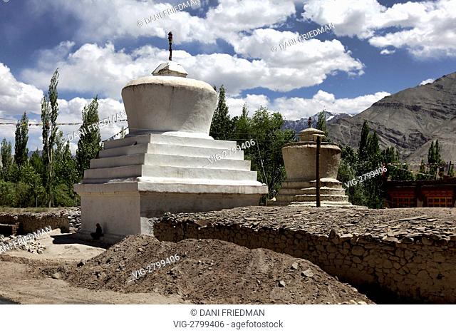 A Ladakhi woman sits at the base of a large Buddhist chorten by her home in the Basgo Village in Ladakh, India. - BASGO VILLAGE, LADAKH, INDIA, 11/07/2010