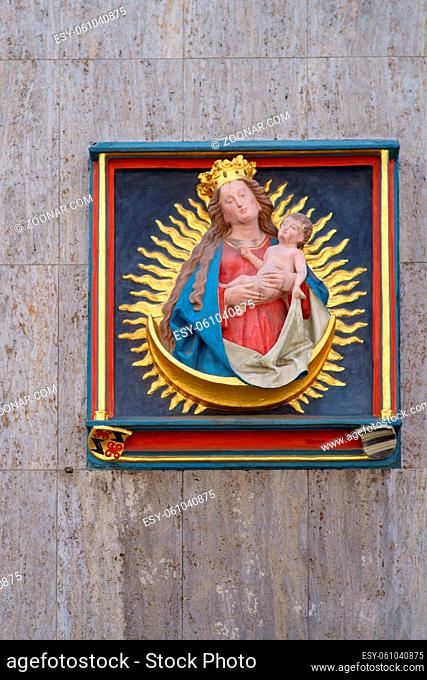 Mainz, Deutschland - Mai 27, 2019: Das vergoldete Relief der Mutter Maria mit dem Jesuskind und einem Strahlenkranz an der Außenfassade eines Gebäudes in der...