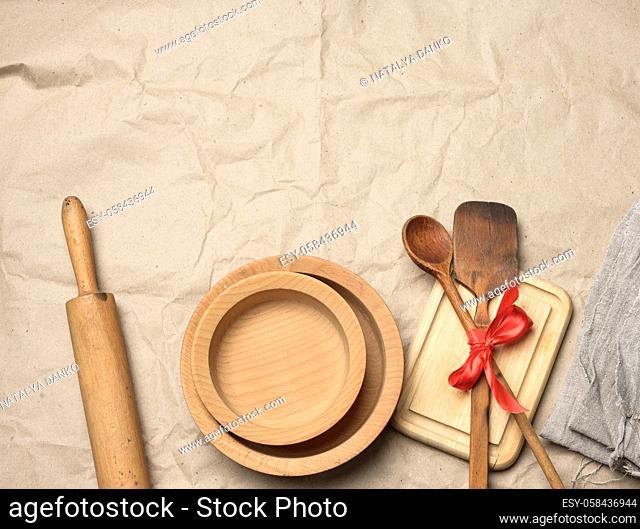 spoon and spatula tied with red ribbon on a brown paper background and wooden rolling pin, top view