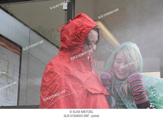2 women at bus stop in the rain