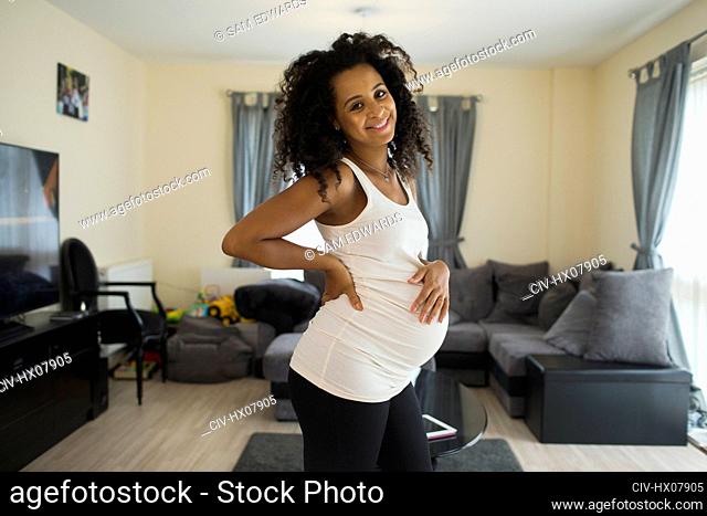 Portrait happy young pregnant woman in living room