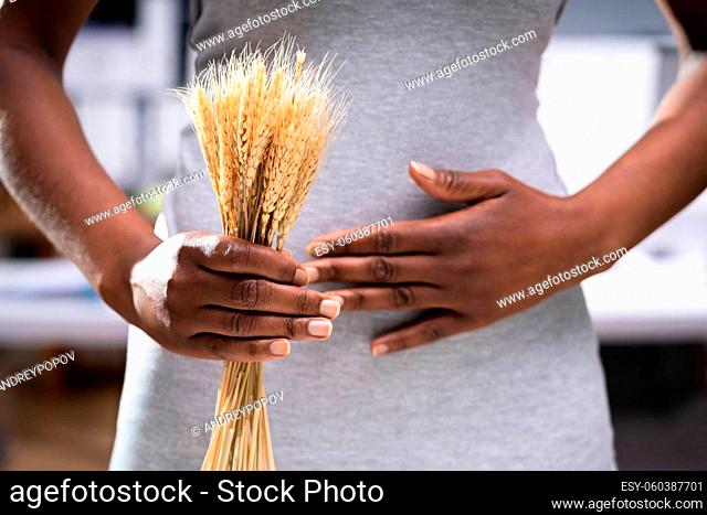 Celiac Disease And Gluten Intolerance. Women Holding Spikelet Of Wheat