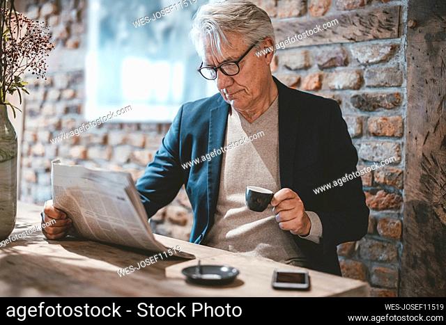 Businessman reading newspaper and having coffee in cafe