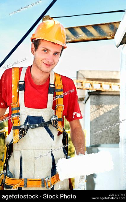 Young smiling painting facade builder worker with roller in work wear