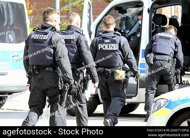 14 April 2021, Hamburg: Police officers walk to their vehicles in front of a refugee shelter. Because of the possible endangerment of two children