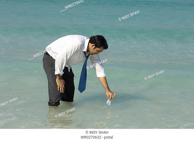 Businessman holding a paper boat