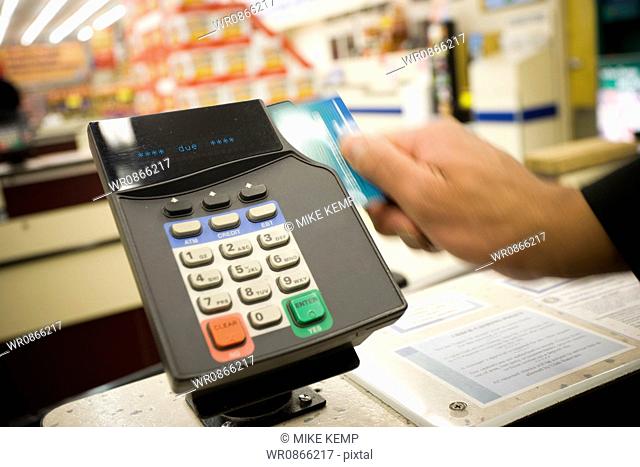 Person swiping debit card at POS machine