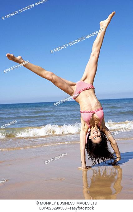 Woman Turning Cartwheel On Beach Holiday