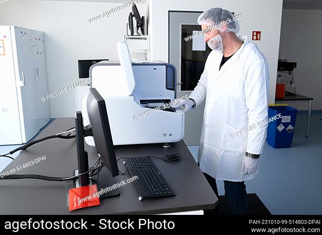 10 October 2023, Saxony, Dresden: Benjamin Lange, service technician, inserts a PCR plate into a ""Modaplex"" diagnostic device in a laboratory of the...