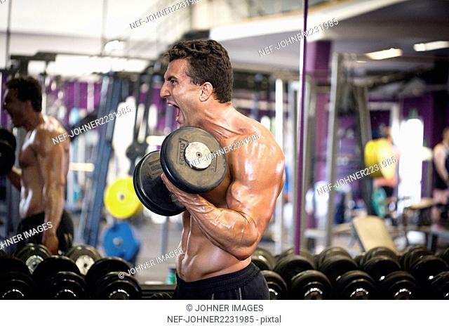Man exercising with dumbbells in gym