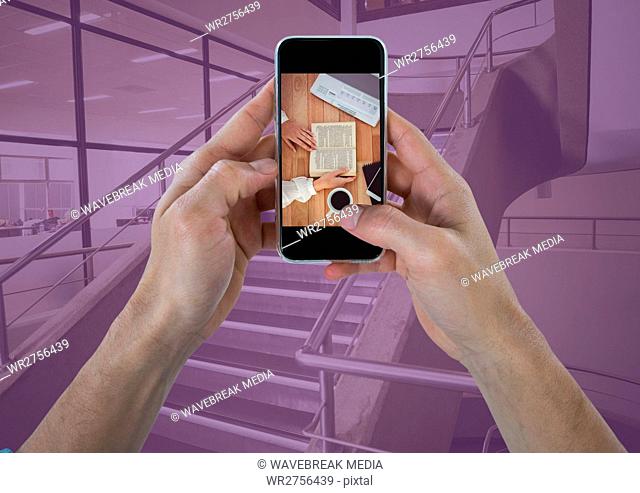 Hands with phone showing desk against stairs with purple overlay