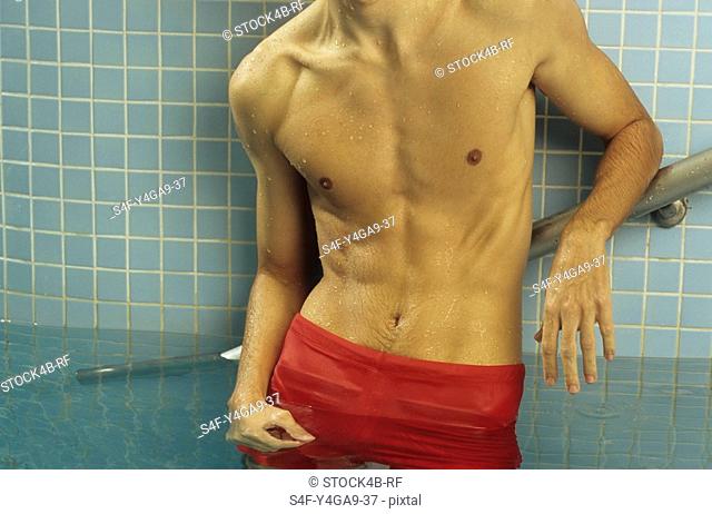 Darkhaired Man leaning against the wall of a Swimming Pool - Baths - Leisure Time