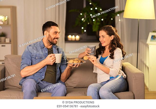 happy couple drinking tea with cookies at home