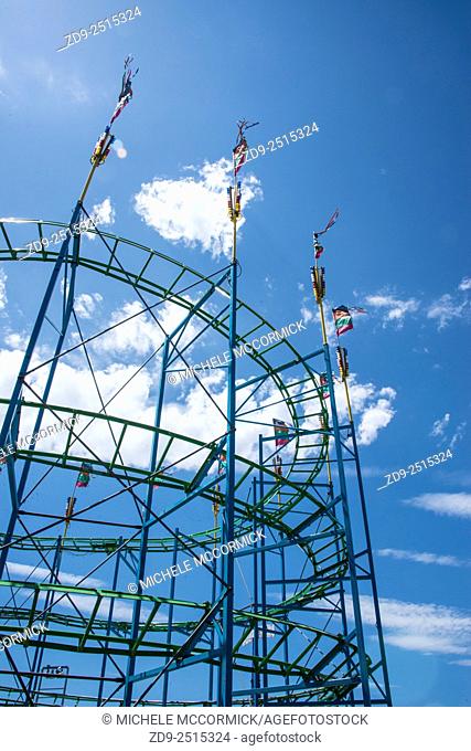 A carnival roller coaster against a blue sky