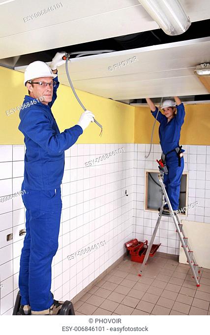 two electricians working on the ceiling