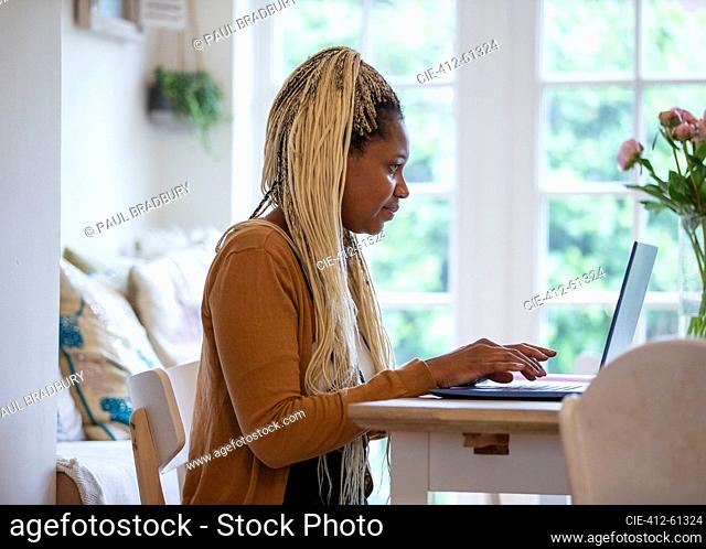 Woman with blonde braids working from home at laptop