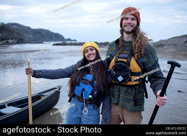 Portrait carefree couple with canoe on ocean beach