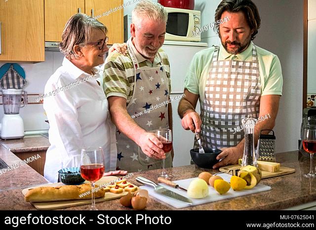 fathers and son adult prepare food and cake in the kitchen for a family scene concept. Daily life at home with two man and a woman
