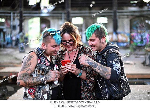 EXCLUSIVE - Author Christine Tramitz shows photos to the punks Basti (r) and Benny at a ruin in Berlin, Germany, 22 September 2016