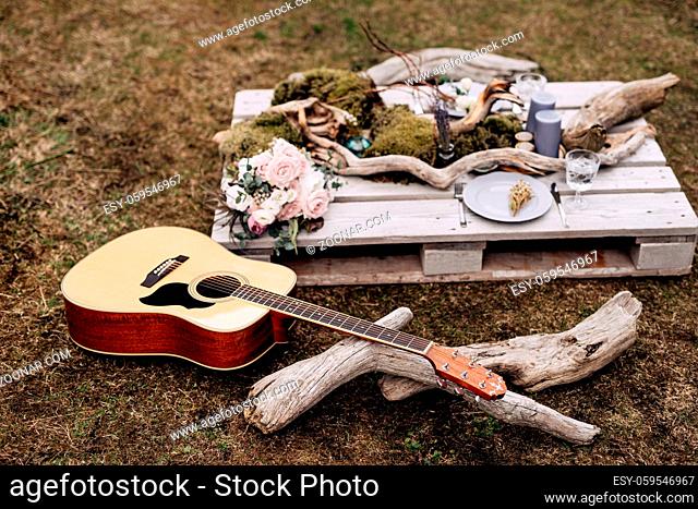 Acoustic guitar on the grass against the background of a wooden stand with items for decoration. High quality photo