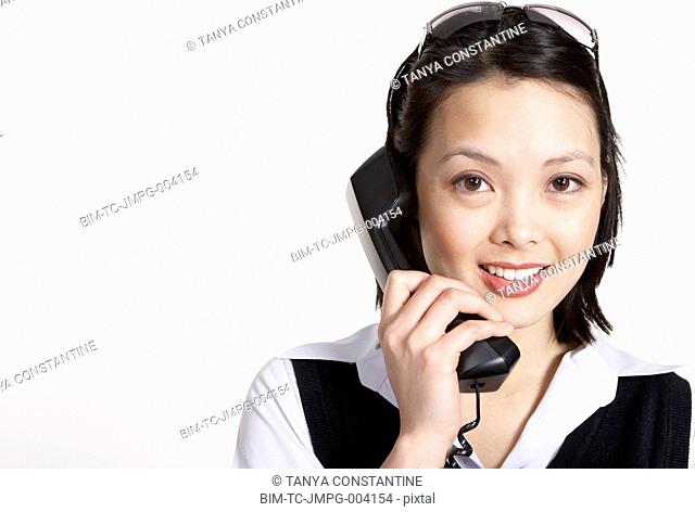 Studio shot of Asian businesswoman talking on telephone