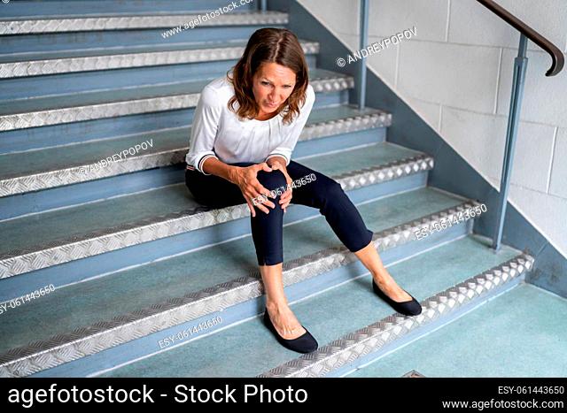 Mature Woman Sitting On Staircase After Slip And Fall Accident