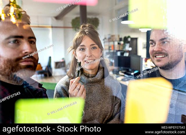 Smiling businessmen and businesswoman discussing over adhesive notes