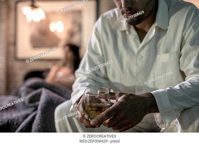 Man sitting on bed having a drink