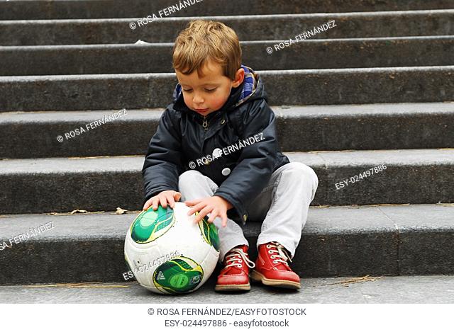 Baby boy playing with a football siting on a step, Madrid, Spain
