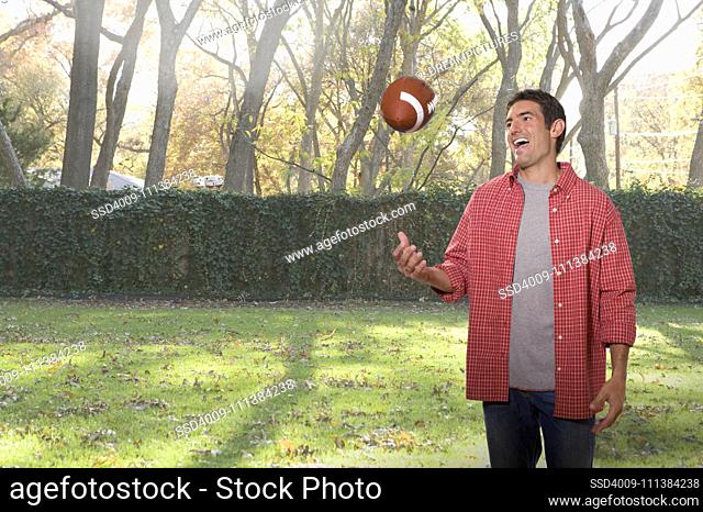 Caucasian man throwing football in backyard