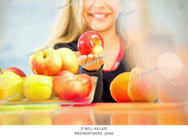 Smiling girl offering an apple