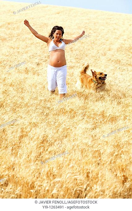 Pregnant woman running in field with her dog