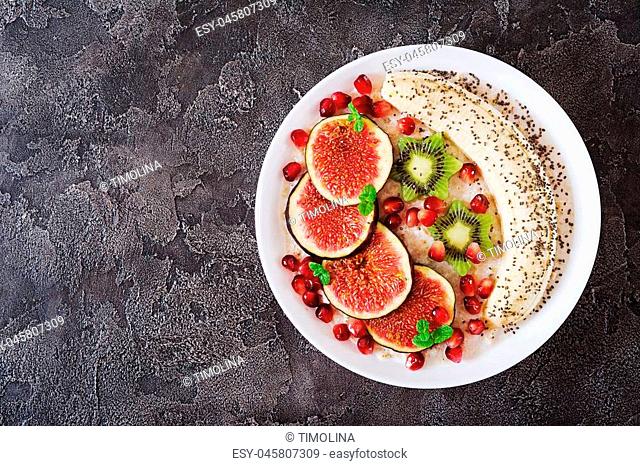 Delicious and healthy oatmeal with figs, kiwi, pomegranate, banana and chia seeds. Healthy breakfast. Fitness food. Proper nutrition. Flat lay