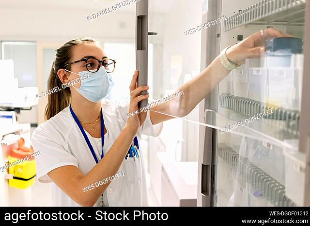 Female doctor taking medicines from cabinet in pharmacy at hospital