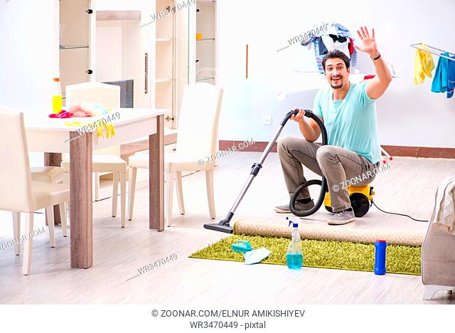 Young man husband doing vacuuming at home