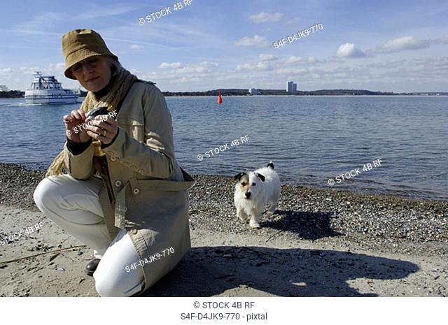 Mature woman collecting shells at the Baltic Sea beach