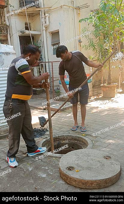 PRODUCTION - 03 October 2023, India, Neu-Delhi: Vinod and Kuldeep open a manhole and remove sludge from a sewer in a residential area in South Delhi