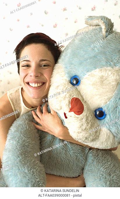 Young woman hugging teddy bear smiling at camera