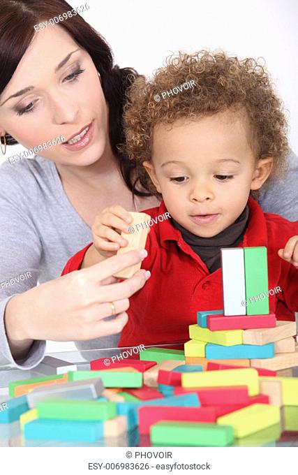 woman and toddler playing with wooden construction game