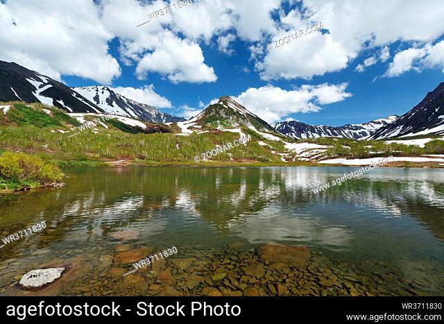 Beautiful summer landscape of Kamchatka Peninsula: view of Mountain Range Vachkazhets, mountain lake and clouds in blue sky on sunny day