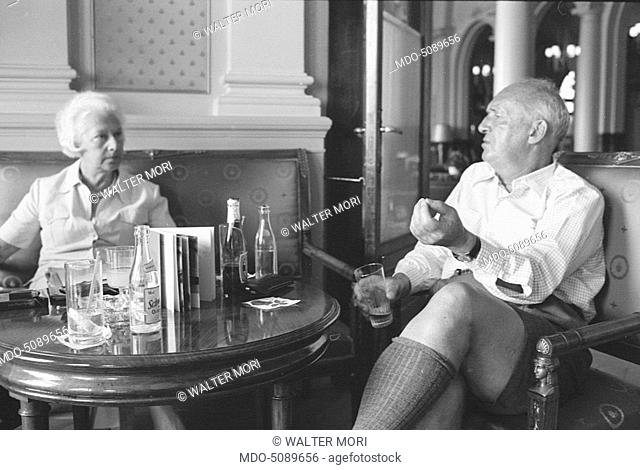 Russian-American writer Vladimir Nabokov sitting and talking in a room of Montreux Palace Hotel, where he is staying. Next to him is his wife Vera Nabokov (Vera...