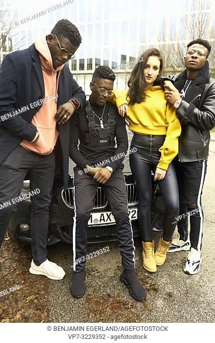 cool fashionable friends gang leaning against car in city, youth culture in Munich, Germany