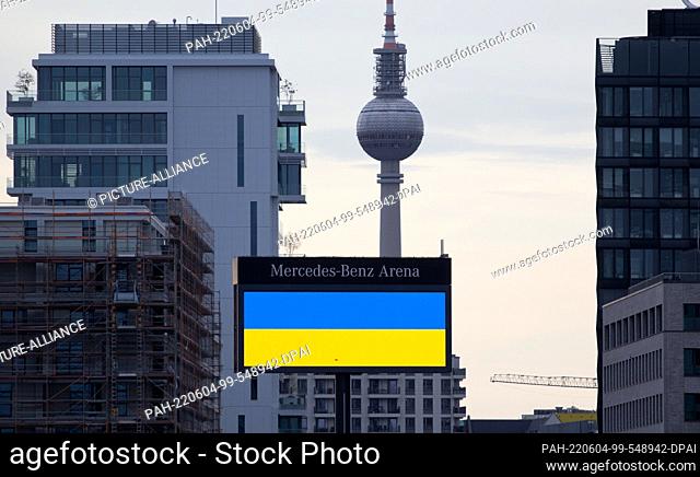 20 April 2022, Berlin: The flag of Ukraine is displayed on a scoreboard of the Mercedes-Benz Arena. Behind it, the Berlin TV tower can be seen