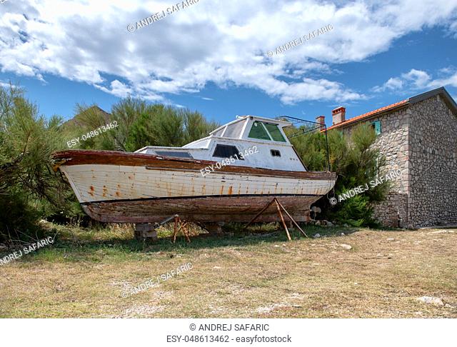 Abandoned boat on shore stone house in background, scene from traditional small fishing village in the Mediterranean, travel and vacation concept for tranquil...