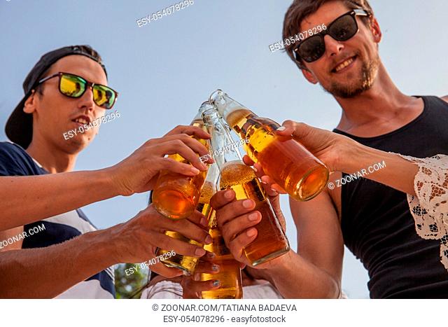 Happy young friends drinking beer outdoors