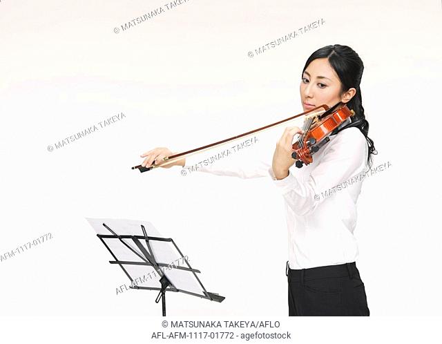 Young woman playing violin with music stand
