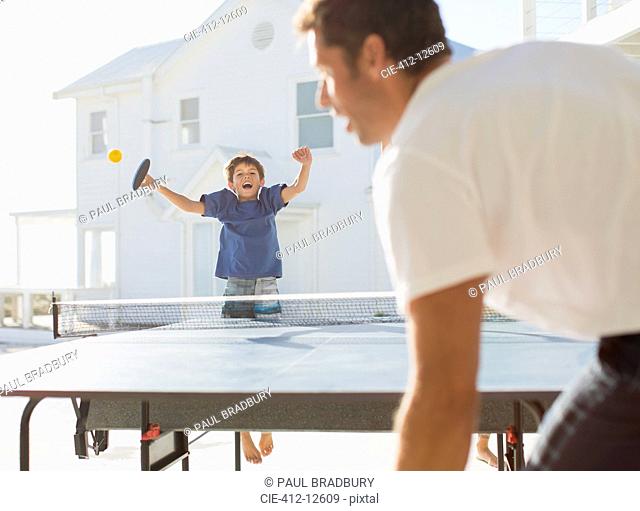 Father and son playing table tennis outdoors