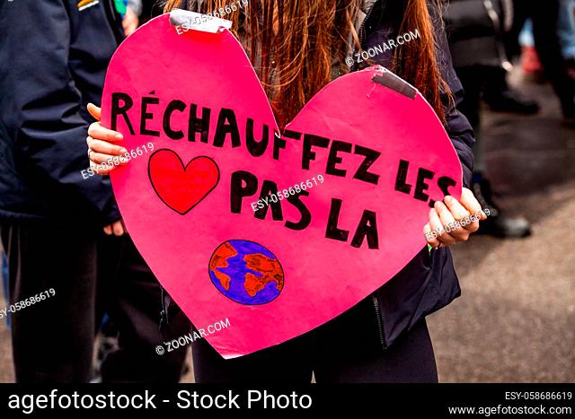 A french placard saying warm the heart not the planet is held by a girl as ecological demonstrators march for the environment in a city center